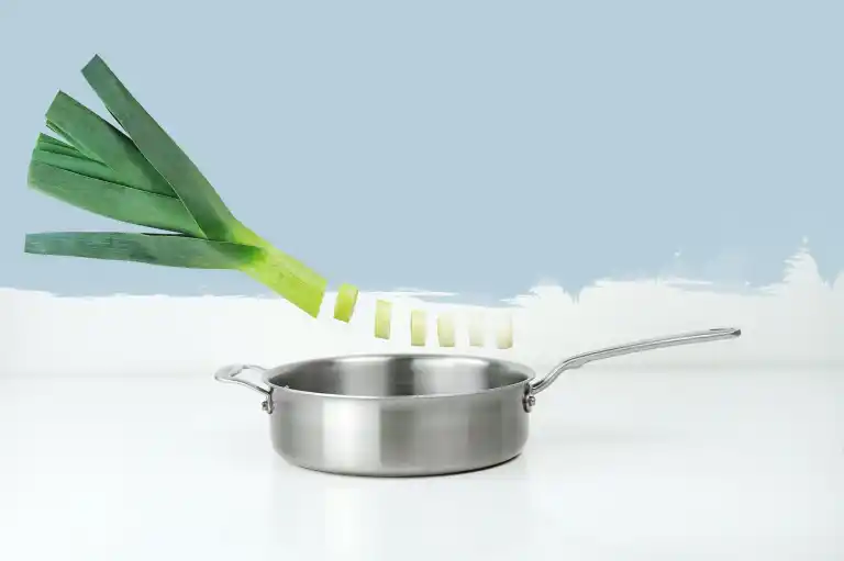 Satu batang bawang prei diletakkan melintang di atas wajan baja berlatar putih.